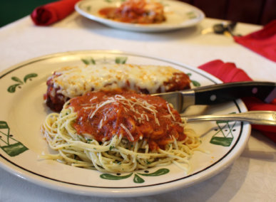 plate of pasta and chicken parmesan with knife and fork