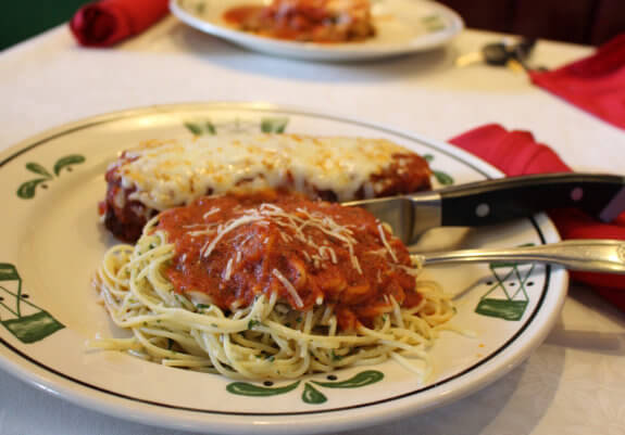 plate of pasta and chicken parmesan with knife and fork