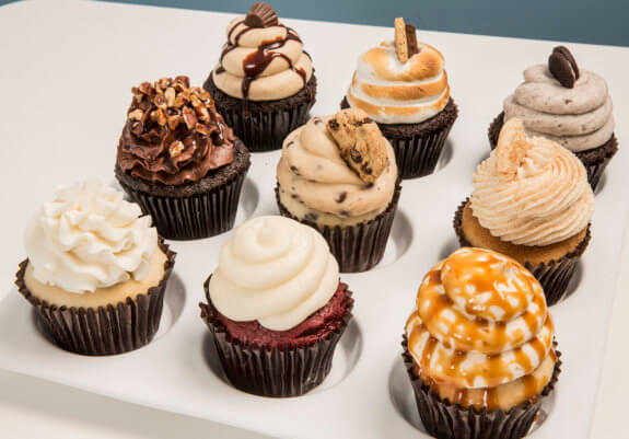 nine different flavored cupcakes on a tray