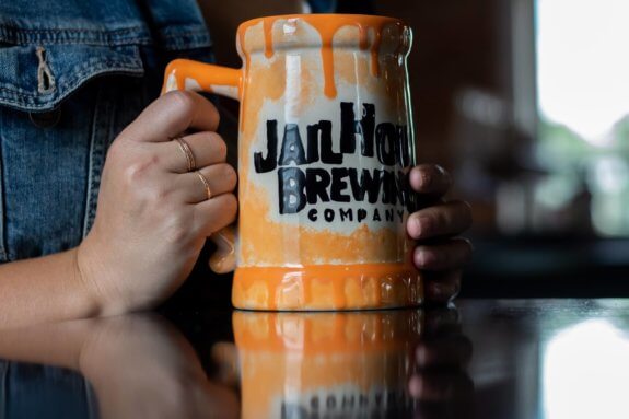 person's hand holding jailhouse brewing company glazed mug