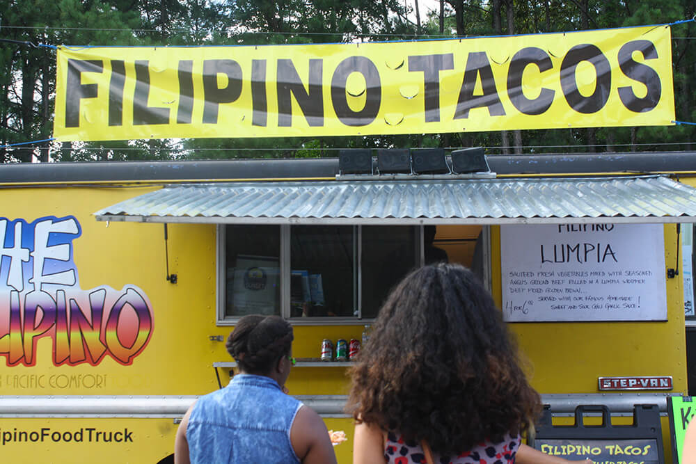 two women standing in front of filipino tacos food truck