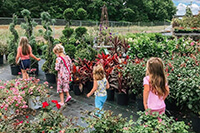 little girls walk through plants at nursery