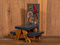 small picnic table with gray top and painted squirrel and cardinal