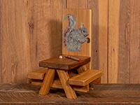 small picnic table with squirrel painted on back and small bat and ball on table