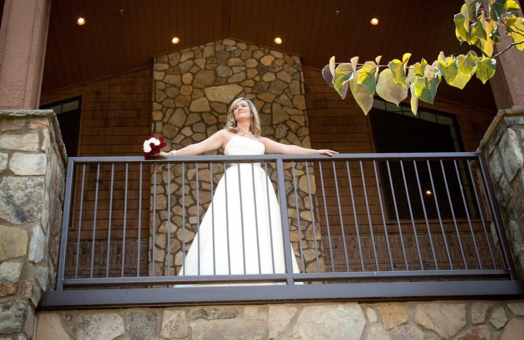 looking up at bride on porch of event center looking out