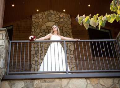 looking up at bride on porch of event center looking out