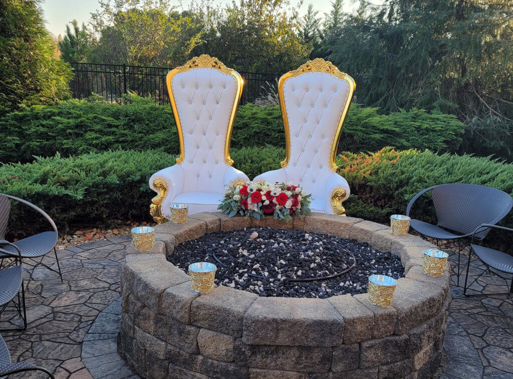 two white upholsetered chairs sitting behind a firepit