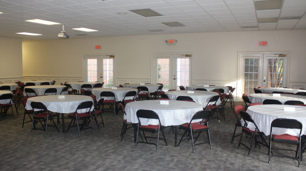 event room with tables set with white tableclothes and red padded folding chairs