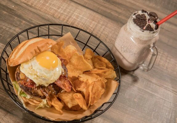 burger with chips and milkshake on table