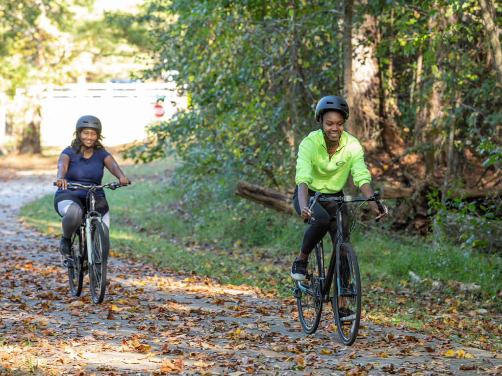 two women riding bikes on wooded path