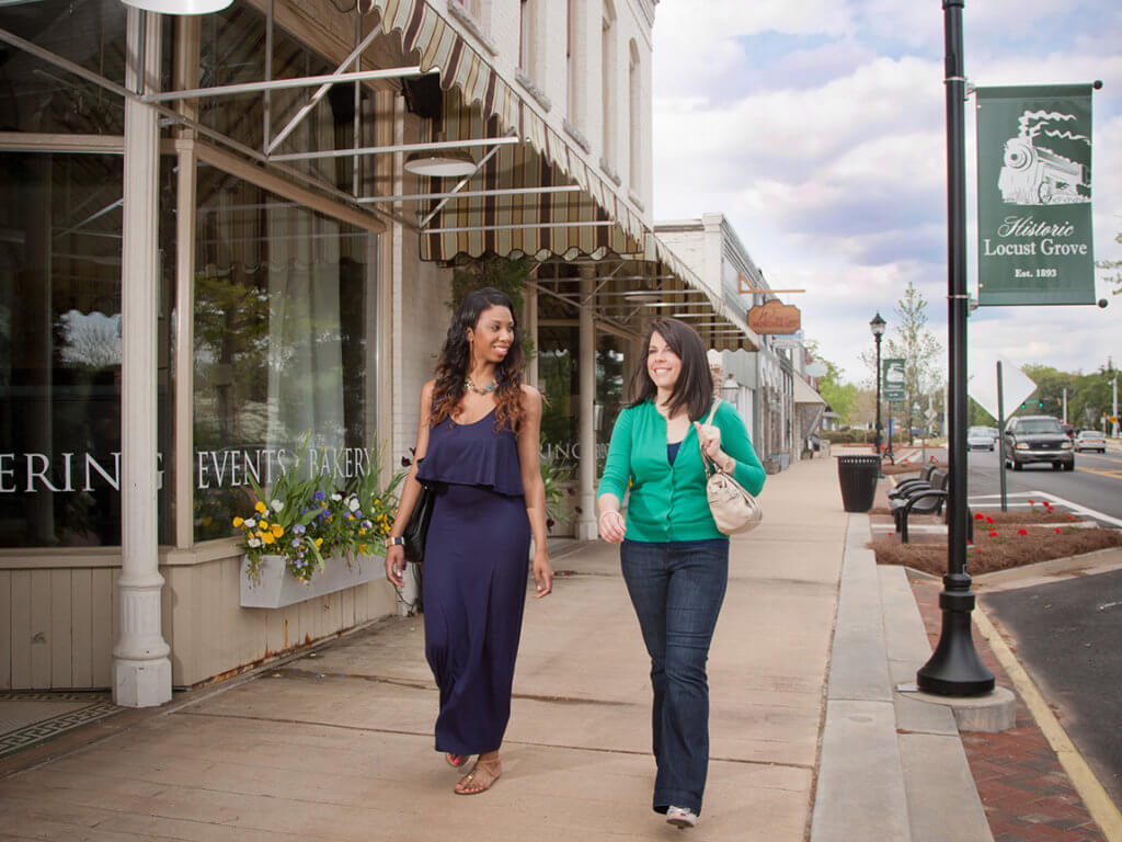 two women walk down a mainstreet past a restaurant