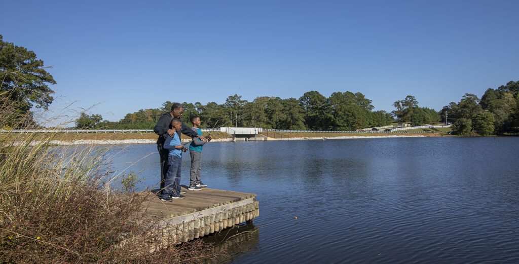 grandfather and grandsons stand on dock fishing