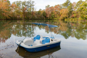Paddleboat floating in lake with fall foliage in background