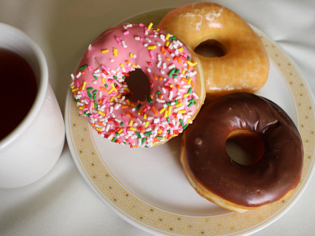 three doughnuts on a plate with tea