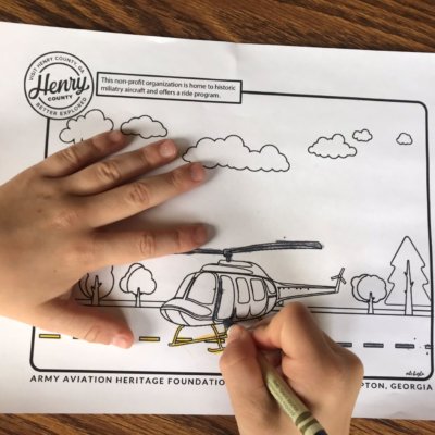 a child's hands coloring a coloring sheet of a helicopter