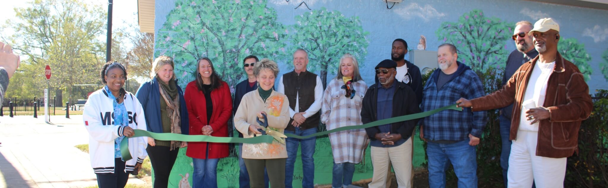 Group Ribbon Cutting in front of mural