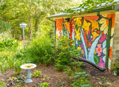 floral mural on textured wall overlooking garden with bird house and bird bath