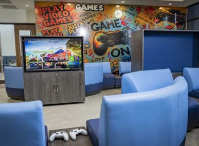 the game room in mt carmel recreation center with controllers and a video game on the screen